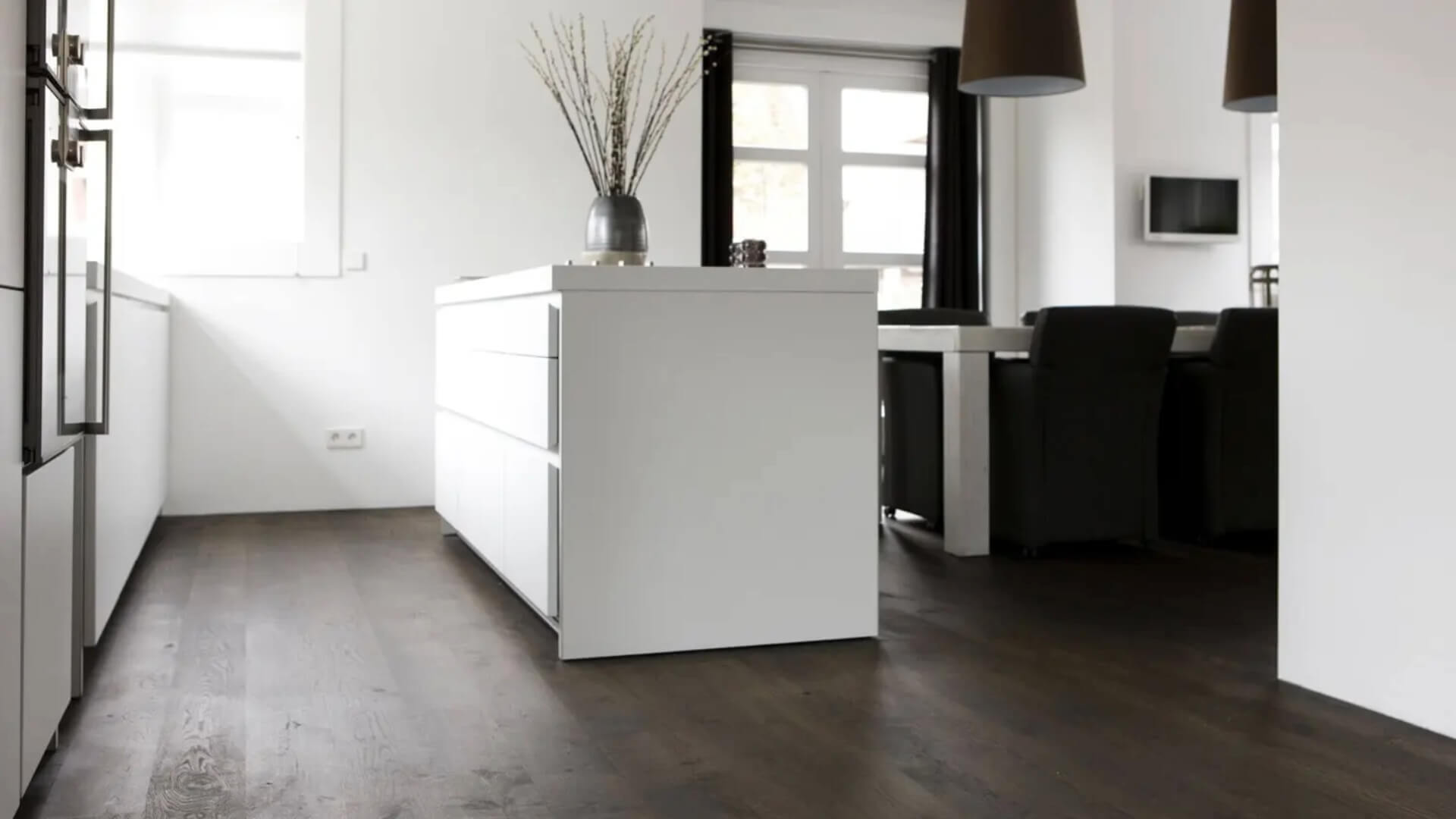 Donkere houten vloer gelegd in witte keuken